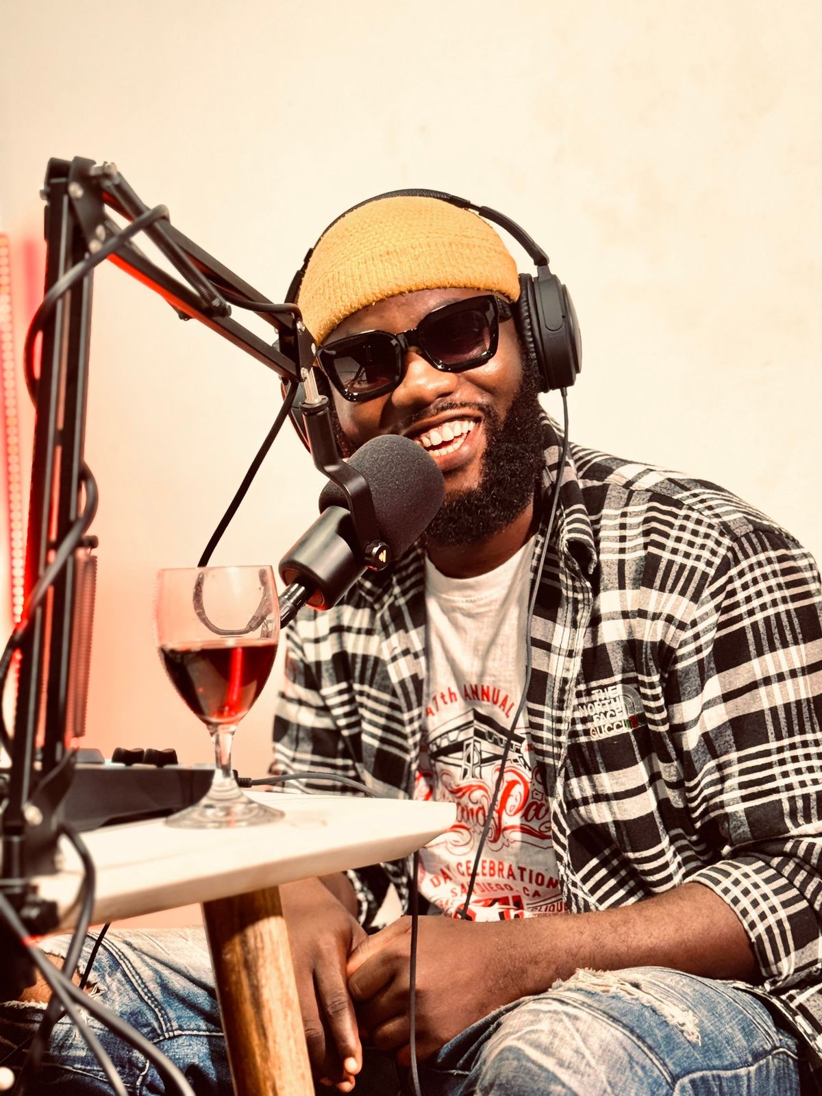 A smiling host in a beanie and headphones at a microphone