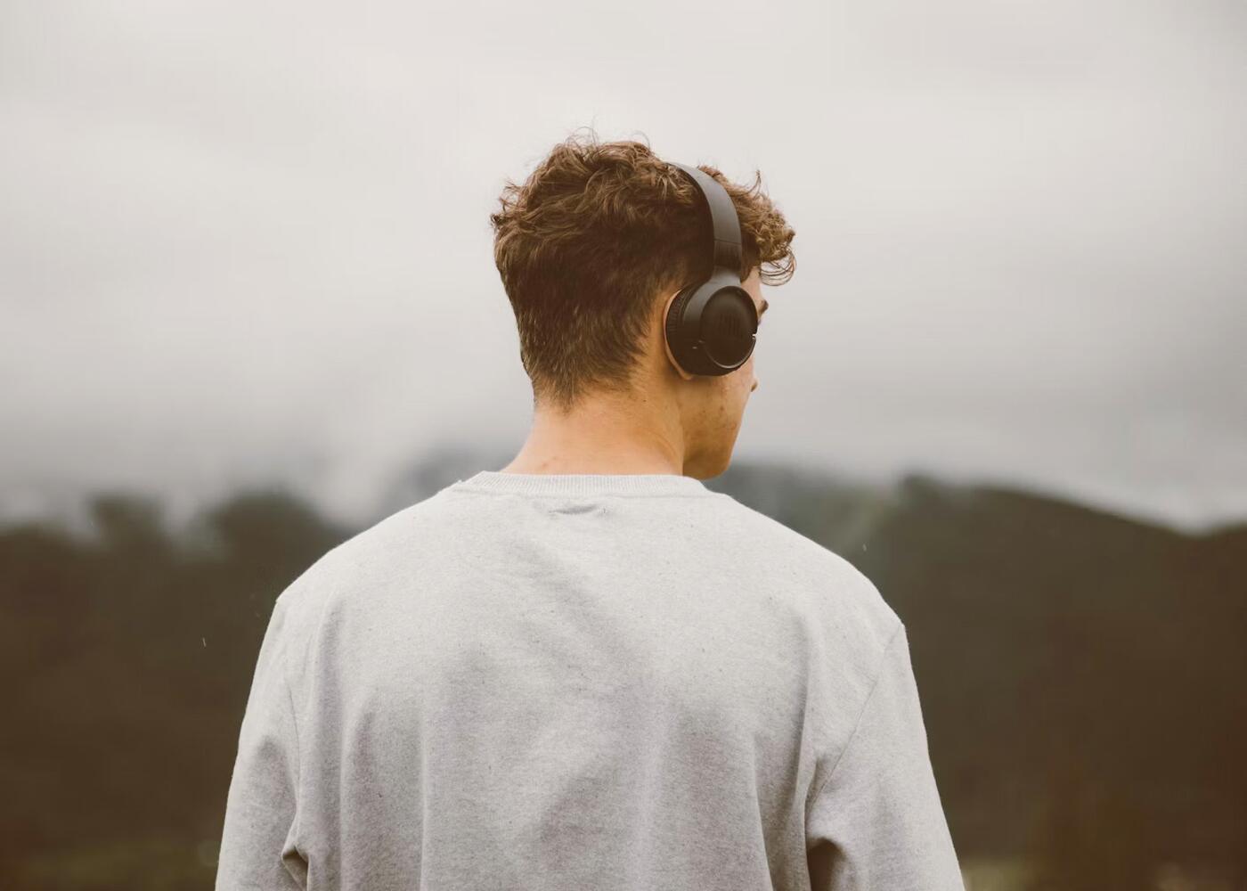 A person in headphones looking out over a misty landscape